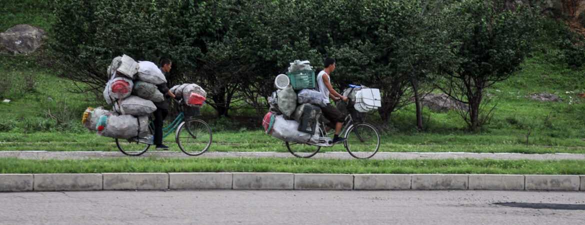 PYNCTM 09/07/2018, Kaesong, North-Korea: two hopeless overloaded bikes are pedaling towards town. Whoever has a bike is a lucky man in North Korea.