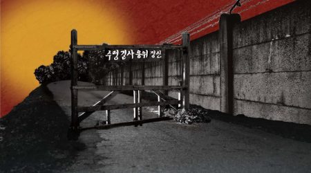 Road with warning sign, wall with barbed wire.